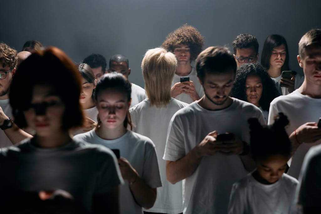 A large group of diverse individuals engrossed in smartphones, conveying themes of social isolation and digital future.